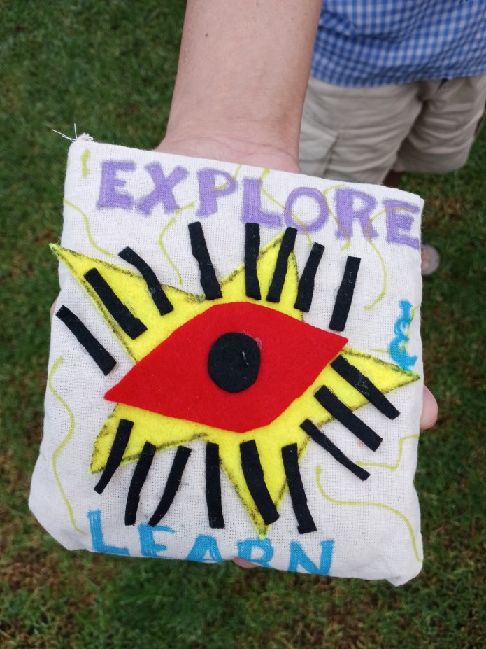 Explore and Learn Corn Throw by Michelle D. An image of an eye created in felt with the worlds Explore and Learn.