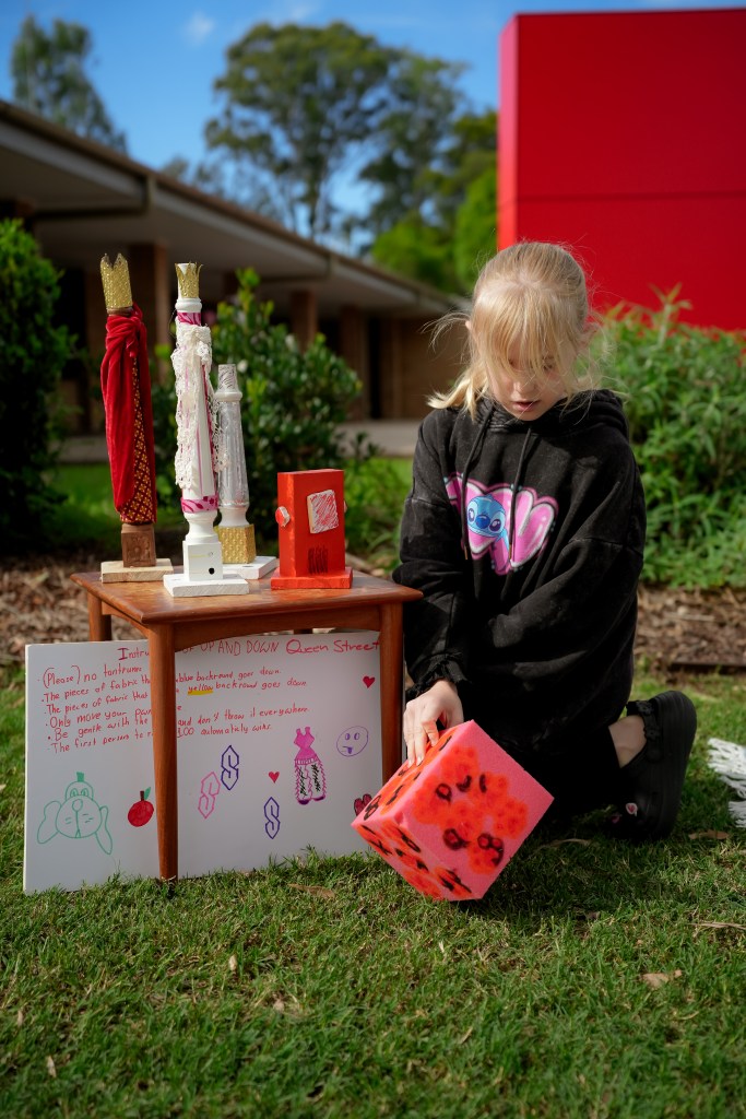 Child with game pawns and game rules for Up and Down Queen Street at St Marys Art and Games Day